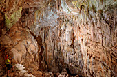 Woman looking at cave with stalagtites and stalagmites, Selvaggio Blu, National Park of the Bay of Orosei and Gennargentu, Sardinia, Italy