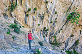 Frau wandert am Selvaggio Blu an Felswand mit Sinter entlang, Selvaggio Blu, Nationalpark Golfo di Orosei e del Gennargentu, Sardinien, Italien