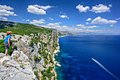 Woman hiking looking over cliff at Golfo di Orosei, Selvaggio Blu, National Park of the Bay of Orosei and Gennargentu, Sardinia, Italy