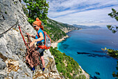 Frau bereitet Abseilen vor, Mittelmeer im Hintergrund, Selvaggio Blu, Nationalpark Golfo di Orosei e del Gennargentu, Sardinien, Italien