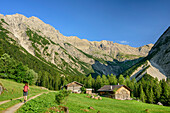 Woman hiking on path crossing alpine huts, valley Fundaistal, Lechtal Alps, Tyrol, Austria