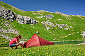Frau öffnet Zelt nahe Bergsee, Gufelsee, Lechtaler Alpen, Tirol, Österreich