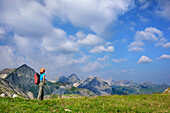 Woman hiking looking towards Lechtal Alps with Oberlahmspitze, Freispitze, Saxerspitze and Wetterspitze, Lechtal Alps, Tyrol, Austria