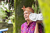 Balinese worker carrying rolled towels, Ubud, Bali, Indonesia