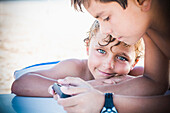 Boys playing with cell phone together outdoors, Bahia De Banderas, Nayarit, Mexico