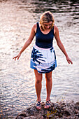 Caucasian teenage girl standing on rocky riverbank, Folsom, California, United States