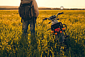 Mari man standing in field with motorcycle, C1