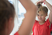 Caucasian girl playing with her hair at mirror, Jersey City, New Jersey, USA