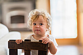 Caucasian baby boy standing behind chair in living room, Santa Fe, New Mexico, USA