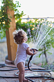 Caucasian baby boy playing with hose on patio, Santa Fe, New Mexico, USA