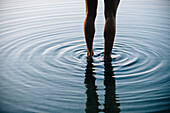 Reflection of legs of Korean woman with ripples in water, Bremerton, wa, USA