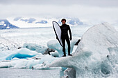 Caucasian surfer carrying board near glacial water, Jokulsarlon, Iceland, Iceland