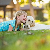 Caucasian girl nuzzling pet dog on grassy lawn, Lehi, Utah, USA