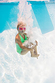 Caucasian girl swimming underwater in pool, Huntington Station, New York, USA