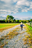 Caucasian girl walking on dirt road on ranch, C1