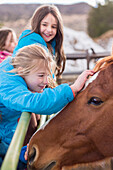 Caucasian girls petting horse on ranch, C1