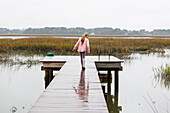 Caucasian girl walking on wooden dock, C1