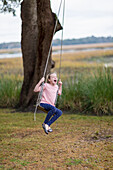 Caucasian girl playing on swing in field, C1