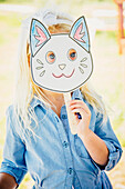 Caucasian girl holding cat mask, Omaha, Nebraska, USA