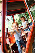 Young boy and young girl playing in a tractor in summer in the country