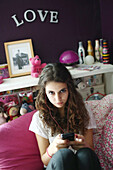 A teenage girl listening to music on her MP3 player on her bed