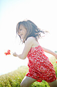 A 7 years girl running with poppies in the hand, on a country lane