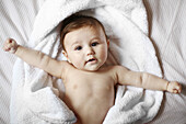 Portrait of a 4 months old baby naked in a towel