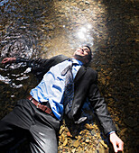 Hispanic businessman laying in water