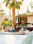 Couple laying in back seat of convertible