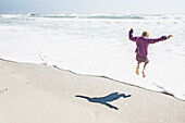 Girl playing in waves on sunny beach