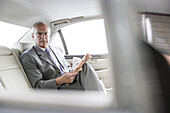 Caucasian businessman reading newspaper in car