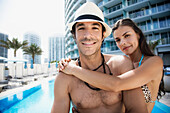 Hispanic couple hugging poolside