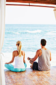 Meditierendes Paar in einer Cabana mit Blick auf den Ozean