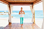 Caucasian woman meditating in cabana overlooking ocean