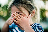 Young Girl Crying with Hands Covering Face