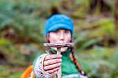 Woman holds up a mushroom in front of her face in the Hoh Rainforest, WA