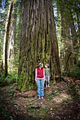 Mother and son look at each other at base of huge Redwood Tree in Redwood National Park, California.