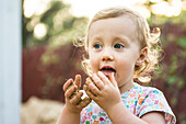 Toddler girl tastes sand from hands, Chico, California.