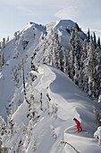 Rachael Burks standing on a cornice looking down on skis. Alpental resort Washington.  January 2007