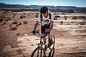 A man in his early thirties mountain bikes the White Rim Trail near Moab, Utah.