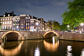 Buildings and arched bridges at the intersection of Herengracht and Reguliersgracht at night, Amsterdam, North Holland, Netherlands
