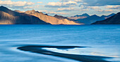 The turquoise, saline water of Tso Pangong, backed by mountains in the evening sun, Ladakh, India, Asia