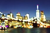 Defocussed view of Brooklyn Bridge and Lower Manhattan skyline at night, New York City, New York, United States of America, North America