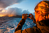 Tourist photographing Tau Island at sunrise, Manua Island group, American Samoa, South Pacific, Pacific