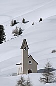 A modern style chapel on a snow covered hillside at Passo Sella in the Dolomites, South Tyrol, Italy, Europe