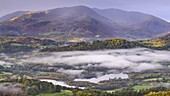 Autumn mist hangs above Elterwater with views beyond to Little Langdale and Wetherlam, Lake District National Park, Cumbria, England, United Kingdom, Europe