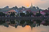 View of Kengtung (Kyaingtong) looking across Naung Tung Lake at sunrise towards the town and gilded stupa of Wat Jong Kham, Kengtung, Shan State, Myanmar (Burma), Asia
