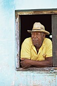 Man leaning out of the window of his house, Trinidad, Cuba, West Indies, Central America