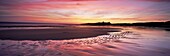 Embleton Bay at sunrise, low tide, with Dunstanburgh Castle in distance, Northumberland, England, United Kingdom, Europe