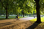 Cyclist and dog walker in Watts Park, Southampton City Centre, Hampshire, England, United Kingdom, Europe